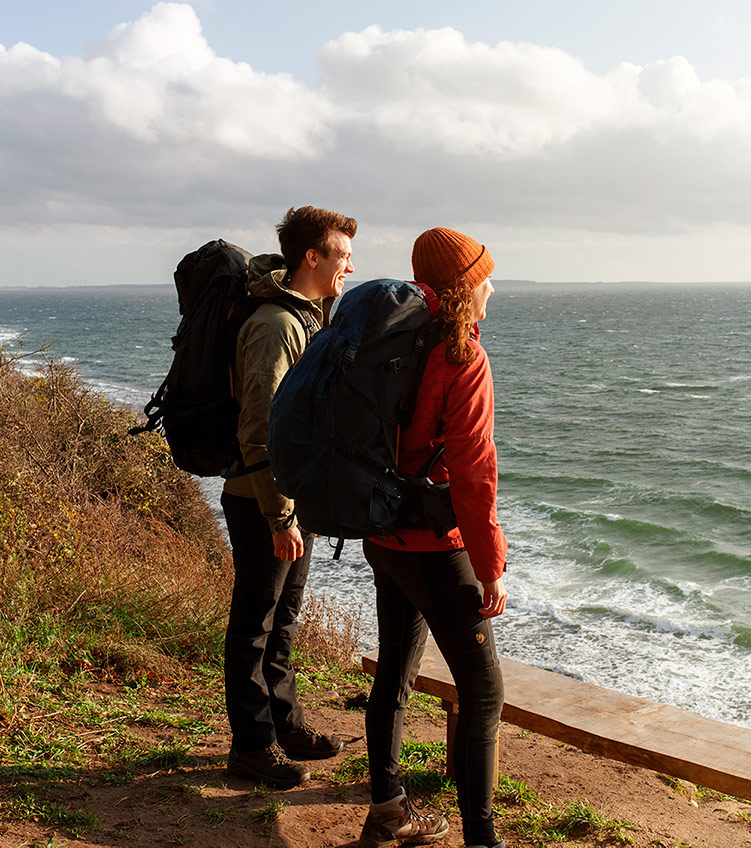 Et ungt par på vandretur kigger ud over havet